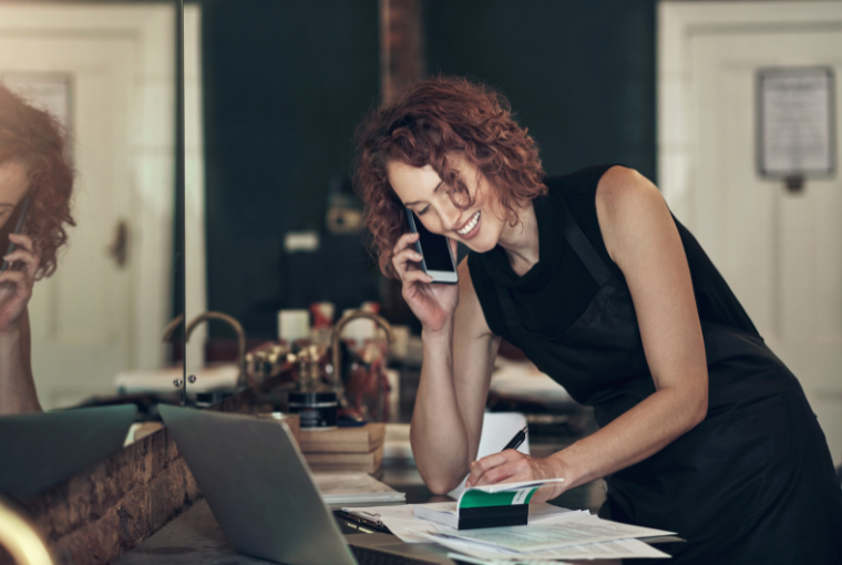 Spa owner on a call with a client and noting down a booking