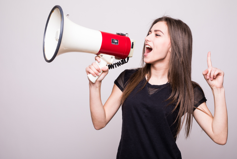 A young woman dressed in black shouting through a white and red megaphone