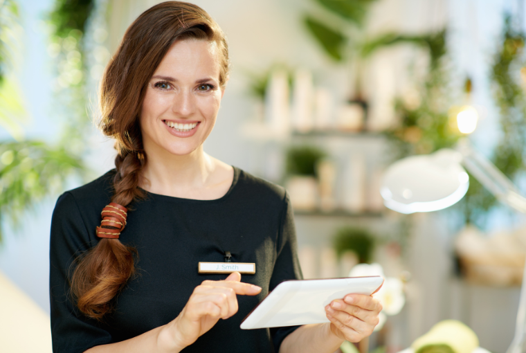 A spa owner holding a tablet smiles at the camera