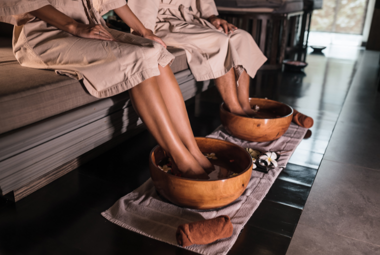 A couple wearing robes enjoying a spa with their feet in wooden basins