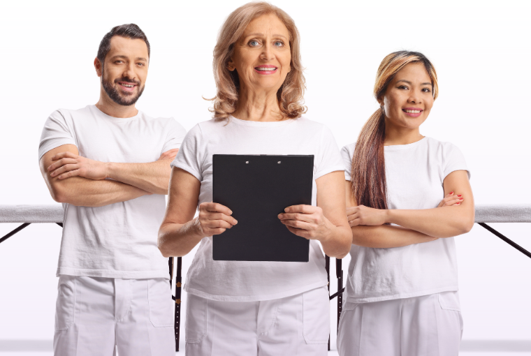 Team of spa employees standing in front of a massage bed nervously holding a clipboard